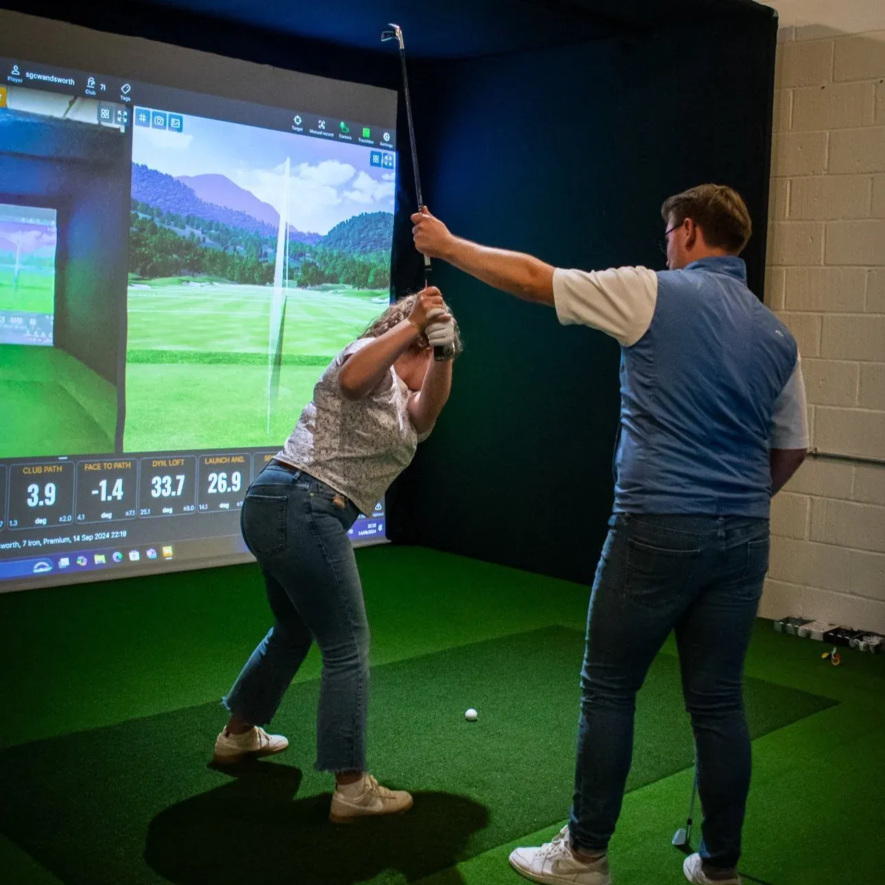 PGA coach working with a golfer in a simulator bay