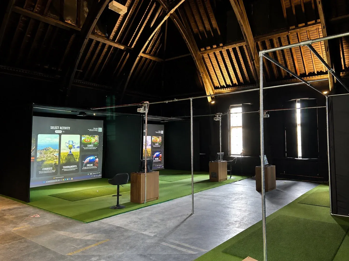 Golfer mid-swing in a Trackman simulator bay at SGC Wandsworth Common