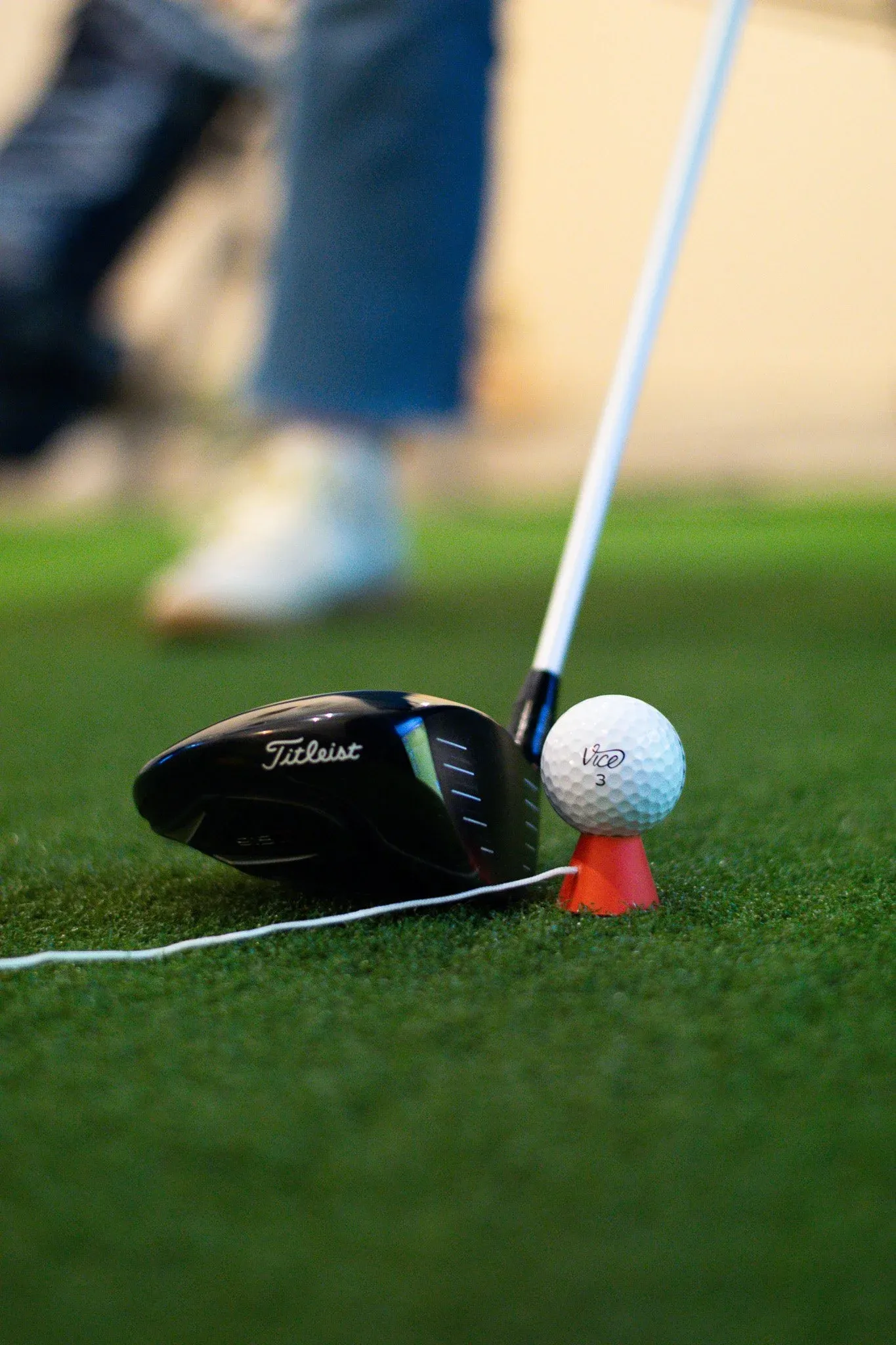 Driver lined up behind a teed-up Vice ball in a simulator bay